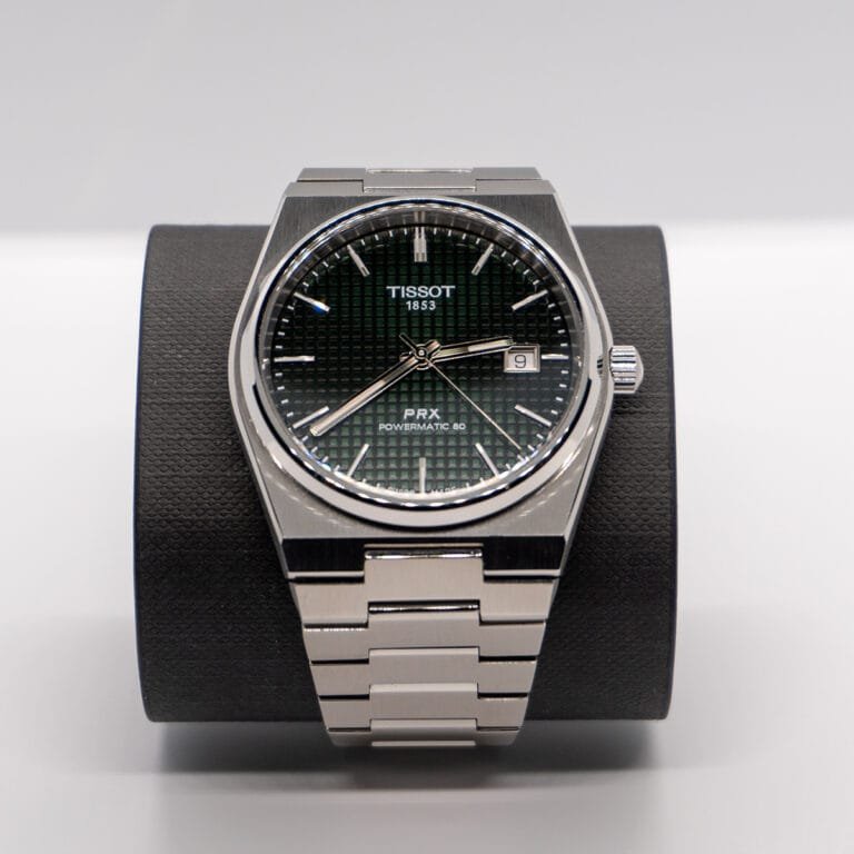 Close-up of a Tissot PRX Powermatic 80 watch with a green textured dial, photographed on a black display stand by Manchester product photographer Blake Hillam.